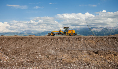 The road machines working on the new road construction site in the asian mountains Tian-Shan
