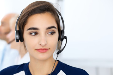 Call center operators at work. Focus at beautiful latin american woman in headset