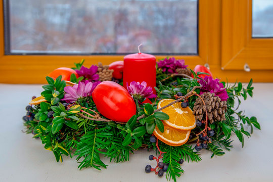 Unique handmade magic Christmas wreath with a red candle and red bell peppers against a wooden winter window - Powered by Adobe