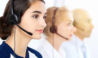 Call center operators at work. Focus at beautiful latin american woman in headset