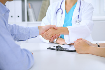 Doctor and patient shaking hands. Family couple at medical exam, just hands at the table. Medicine concept