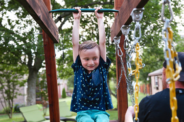 Young Child Swinging on the Monkey Bars Smiling