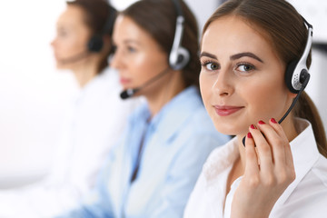 Call center. Group of operators at work. Focus at beautiful business woman in headset