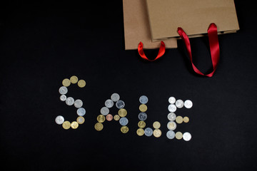 SALE written with coins and paper bags.