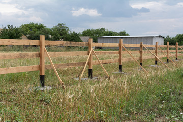 Ranch style fence. Rural wooden fence on green grass at farm ranch land in Shagany, Ukraina.