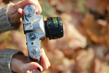 Fototapeta premium Vintage camera in hand on blurred background. Close-up, focus on camera controls