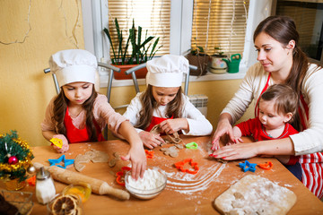 Merry Christmas and Happy Holidays. Family preparation holiday food. Mother and daughters cooking Christmas cookies.