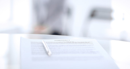 Contract with a pen and blurred business people on the background, close-up
