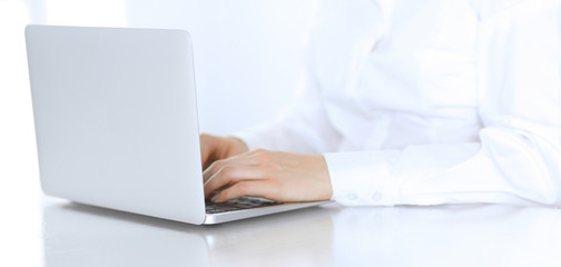 Fototapeta premium Close-up of business woman hands typing on laptop computer. Secretary at work in office