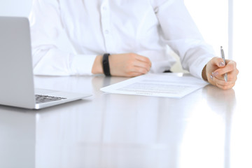 Fototapeta premium Close-up of female hands with pen over document, business concept. Lawyer or business woman at work in office