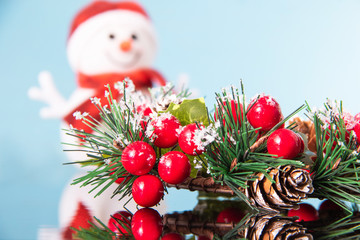 Snowman with beautiful Christmas wreath on a blue mirror surface , traditional decoration for the new year for the holiday