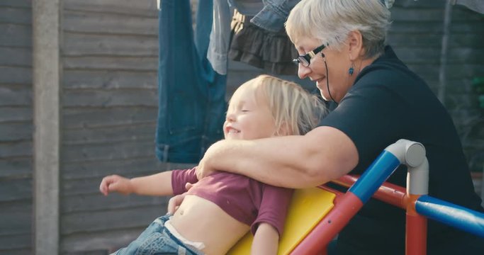 Grandmother and toddler playing pon slide in garden