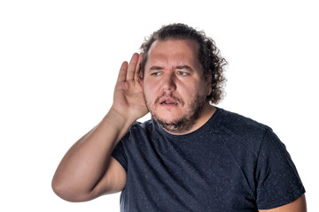Fat man, trying to hear someone putting his hand on his ear, standing on a white background
