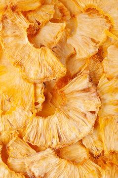 Dried pineapple slices (chips) background. Dehydrated crispy fruit slices. Heap, pile of sun dried crunchy pineapples.