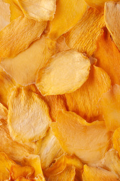Dried mango slices (chips) background. Dehydrated crispy fruit slices, pieces. Heap of sun-dried mango fruit.