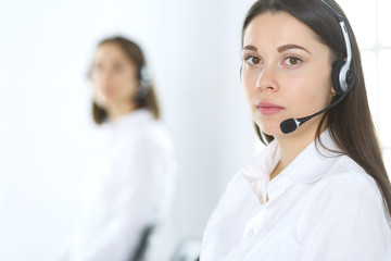 Group of call center operators at work. Focus on beautiful business woman in headset