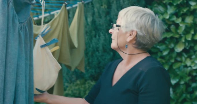 Senior woman drying laundry outdoors