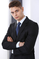 Young businessman standing in office with arms crossed. Business concept