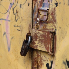 Old rusty iron padlock on abandoned garage door close-up - security, theft protection