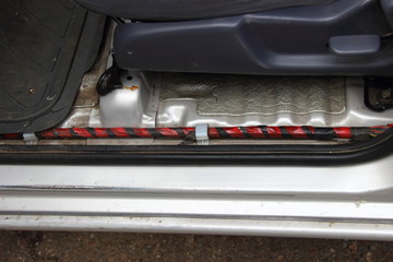 The wiring harness in the doorstep of the car with the removed plastic plate on the background of...