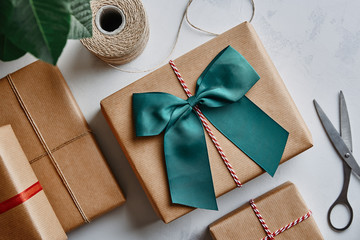 Christmas presents wrapped in brown paper with twine, bow and scissors. View from above