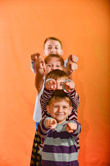 Four children stand in a row and point their fingers forward to the age on a yellow background, the younger ones look out for the older ones.