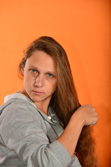 Fototapeta premium Beautiful and young girl holding hair with hands on a yellow background.