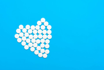 Heart of white pills on white blue background. Free space for text.