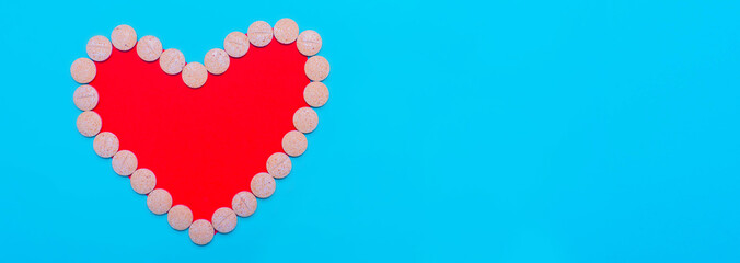Heart of red pills on blue background. Free space for text.