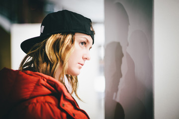 Face profile of trendy girl in red jacket wearing stylish cap