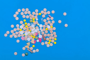 Assorted pharmaceutical medicine pills, tablets and capsules on blue background. Copy space for text. Medicine. top view