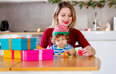 beautiful mother with son wrapping a gift boxes against the background of the scenery for Christmas in the kitchen