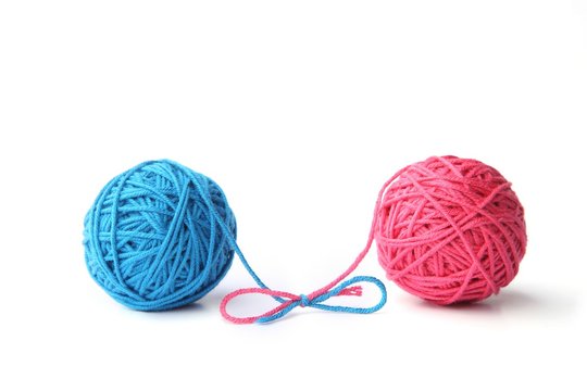 Two pink and blue cotton thread balls tied in bow isolated on white background.  Different color pink and blue thread balls. 