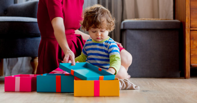 beautiful mother with son wrapping a gift boxes against the background of the scenery for Christmas in the kitchen