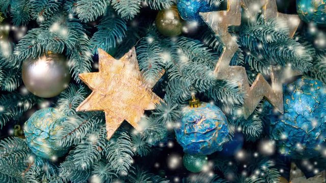 Different decorative Christmas-tree toys close-up, decorations for Christmas tree, green spruce branch needles, snow snowfall snowstorm snowflakes. Winter Christmas New Year background. Cinemagraph