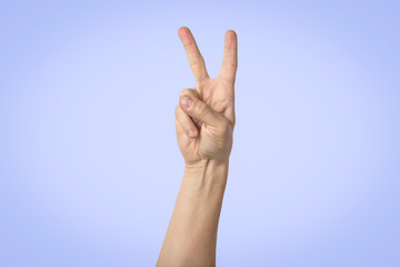 Male hand raised up and showing a gesture of peace with two lifted fingers on a blue background. Gesture Yo. Concept of power, unity, rap respect