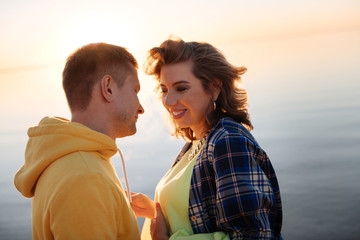 Romantic couple standing near the river at the sunset