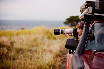 Woman photographing while sitting in car at Queen Elisabeth National Park © Cavan for Adobe