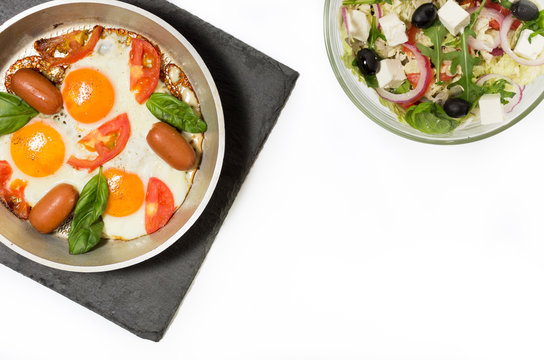 Scrambled eggs and salad. Fried eggs in the pan.