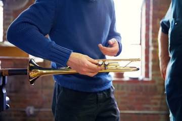 Midsection of man holding trumpet while working in workshop © Cavan for Adobe