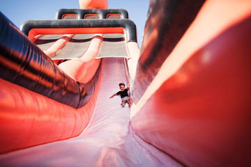 Naklejka premium Happy boy on inflatable slide at amusement park