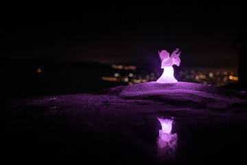 christmas angel on blur bokeh city lights at night on background. Little white guardian angel in...