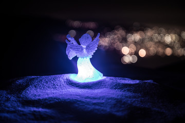 christmas angel on blur bokeh city lights at night on background. Little white guardian angel in...