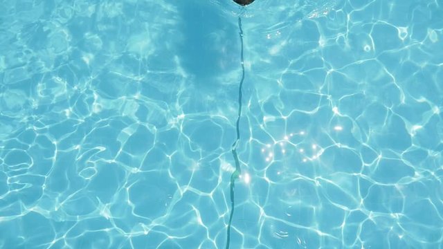  Inspiring up down view of a smiling blond woman in blue bikini relaxing and swimming backstroke in a swimming pool with turquoise waters in slow motion