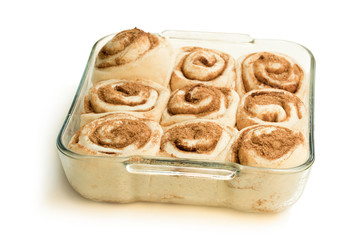 Raw cinnamon buns in clear glass baking form isolated on white
