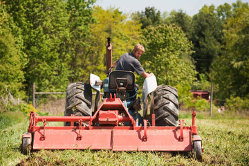 Farmer looking at harrow while riding tractor on field © Cavan for Adobe