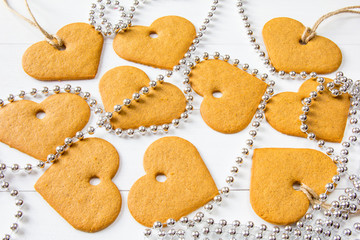 Happy Saint Valentine's Day. Ginger cookies of a heart shape with silver beads at white table background