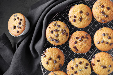Freshly baked choco chip muffins cooling off on wire mesh on dark background with linen towel