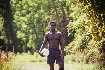 Fototapeta premium Portrait of confident shirtless young man with soccer ball