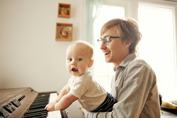 Father assisting son in playing piano at home © Cavan for Adobe
